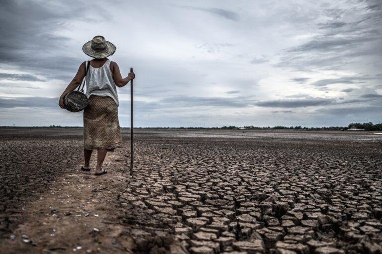 Women standing on dry soil and fishing gear, global warming and water crisis due to climate change